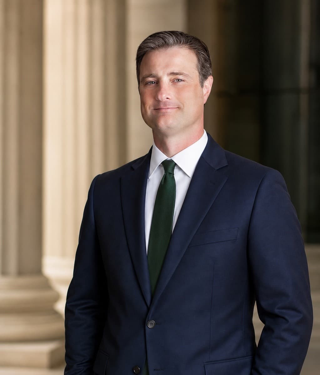 Joe Green wearing a navy suit and forest-green tie